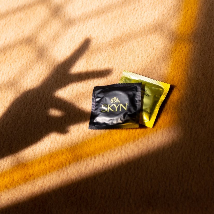 Hand shadow over two SKYN condom sleeves Hand shadow over two SKYN condom sleeves